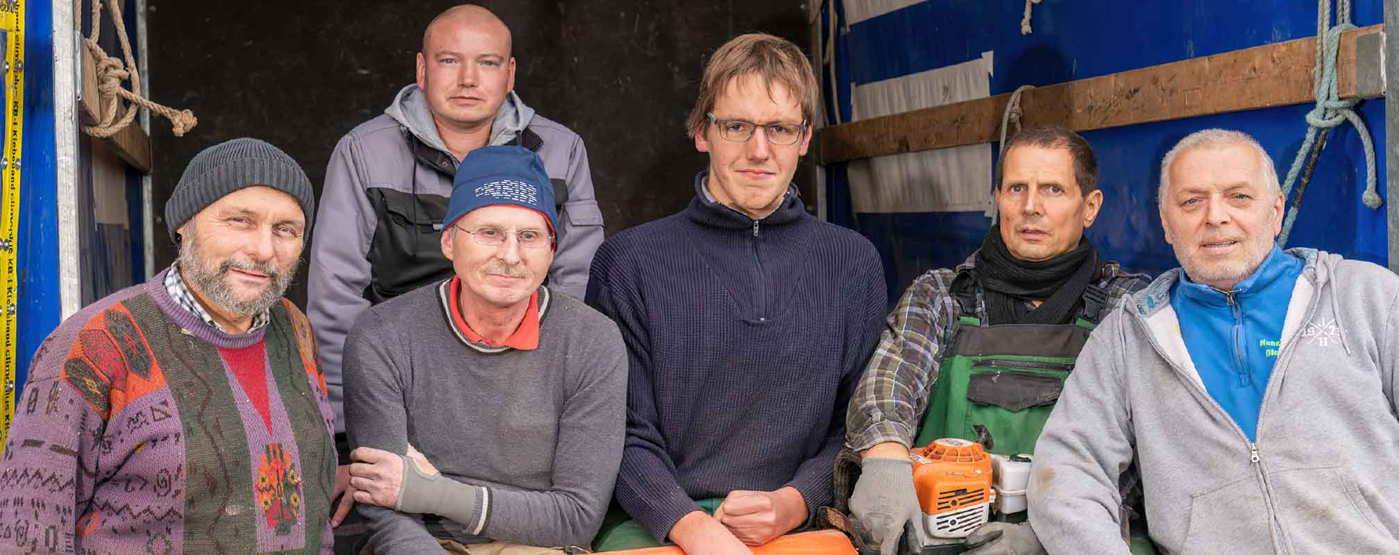 Gruppenfoto: Inga-Mitarbeiter sitzen auf der Ladefläche eines LKWs